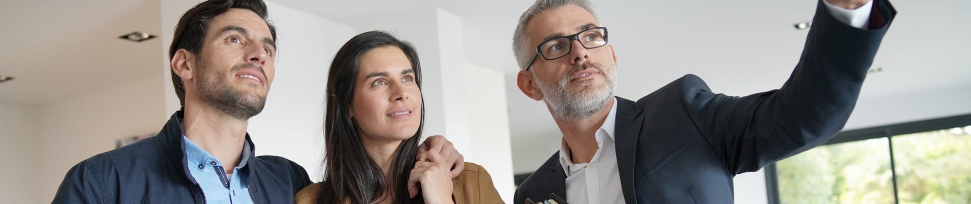 Een man en vrouw bezichtigen een woning samen met een mannelijke makelaar